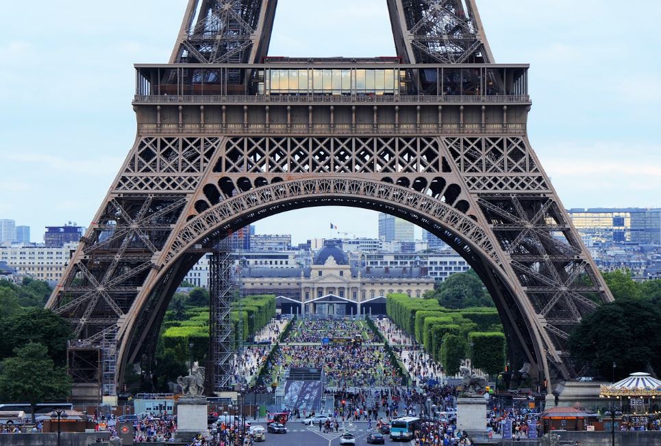 Blick durch die untere Bogenkonstruktion des Eiffelturms im belebten Paris