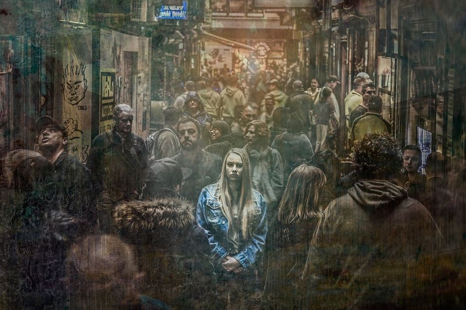 Eine junge Frau schaut nachdenklich aus einer dicht bevölkerten Seitenstraße in Richtung des Betrachters