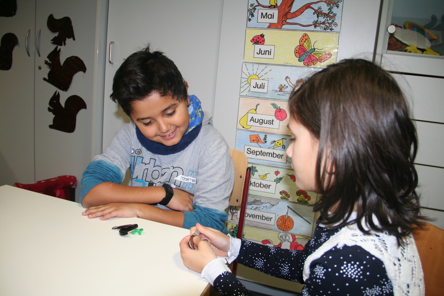 Eine Schülerin und ein Schüler beim Betrachten ihrer Hörgeräte