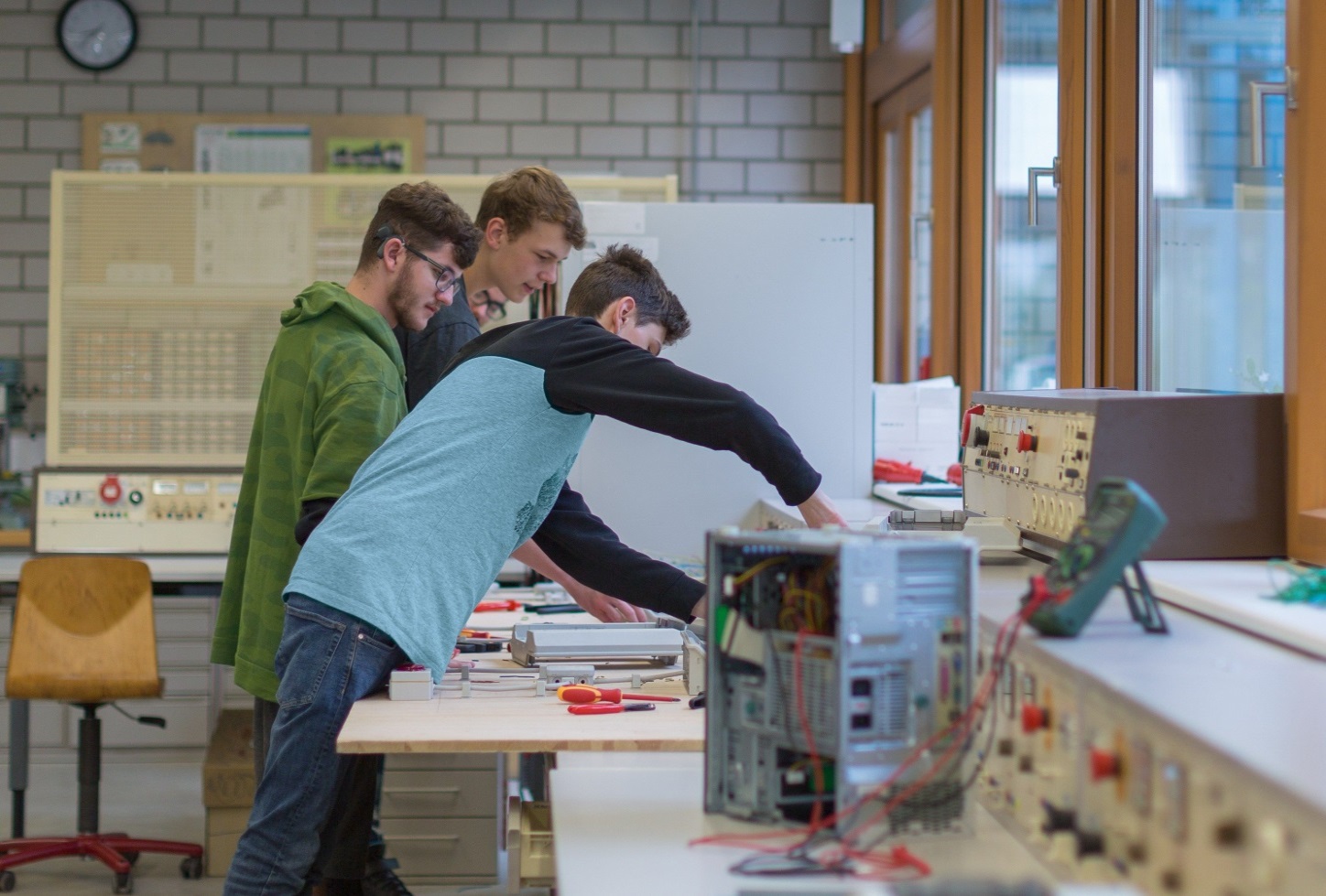Berufliche Schule, Werkstatt, 3 Schüler schrauben an einem PC.