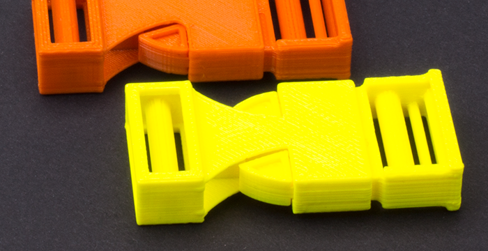 zwei Steckklammern, gelb und orange, auf schwarzem Hintergrund 1