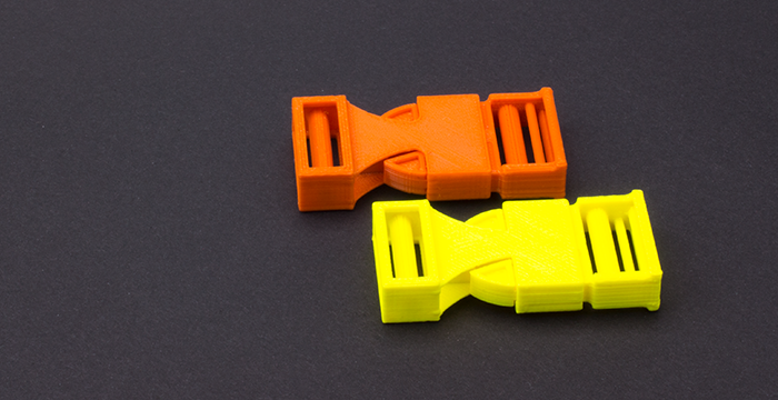 zwei Steckklammern, gelb und orange, auf schwarzem Hintergrund 2