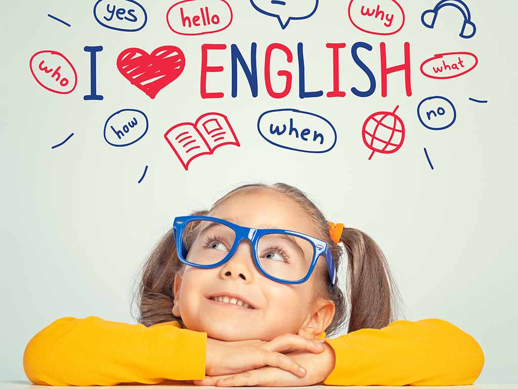 Das Bild zeigt ein fröhliches Mädchen mit blauer Brille, das nachdenklich nach oben schaut. Über ihr sind englische Begriffe wie "yes", "hello", "who", "when" und "I ❤️ English" dargestellt. Dies vermittelt die Freude am Englischlernen
