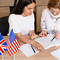 Zwei Schülerinnen bei Lernen vor einer englischen und amerikanischen Flagge