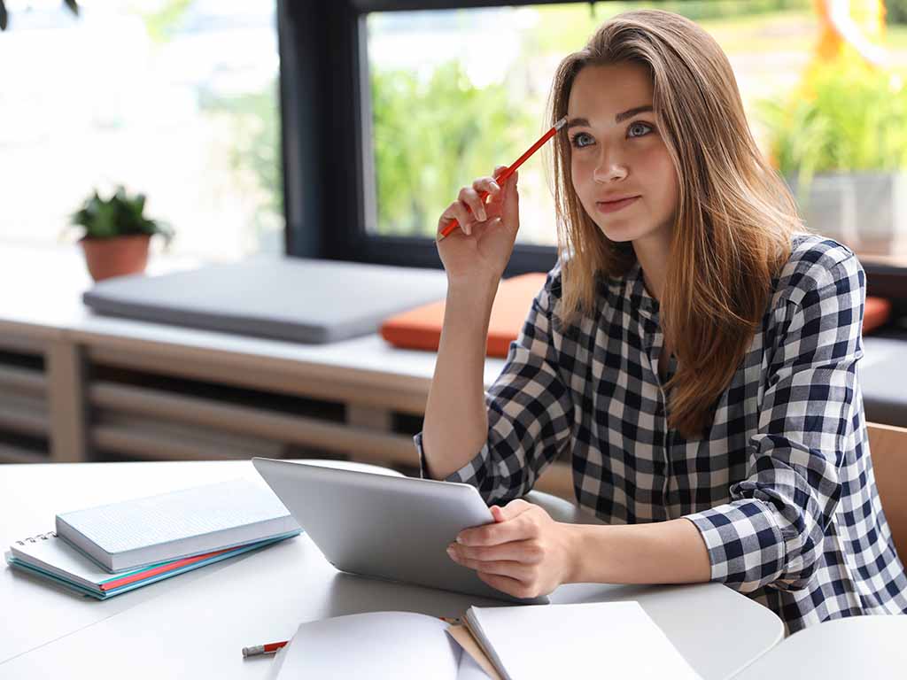 Das Bild zeigt das Reichstagsgebäude in Berlin, Deutschland. Im Vordergrund weht die deutsche Flagge. Auf dem Gebäude ist die Inschrift DEM DEUTSCHEN VOLKE zu sehen. Im Hintergrund ist die markante gläserne Kuppel des Reichstags zu erkennen. Der Himmel ist klar und blau