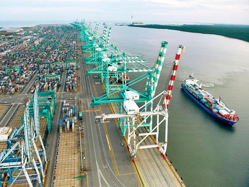 Wirtschaft Containerhafen - Ein Schiff fährt an Kränen vorbei
