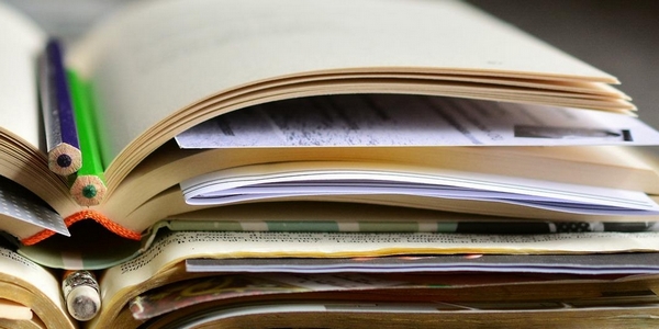 Aufgeschlagene und aufeinander gestapelte Bücher mit zahlreichen Zetteln als Seitenmarkierungen und eingelegten Stiften zeugen von einer regen inhaltlichen Auseinandersetzung.