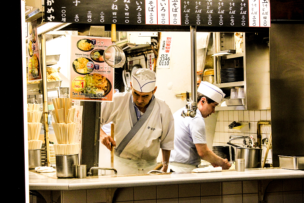 Zwei Männer in einem asiatisch anmutenden zur Straße hin geöffneten Restaurant